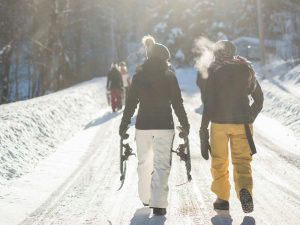 two snowboarders walking up a snowy trail