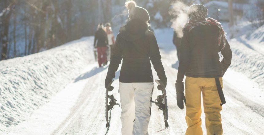 two snowboarders walking up a snowy trail