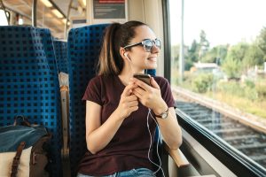 woman listening to streaming audio on her commute, woman streaming audio on the train, premium streaming audio